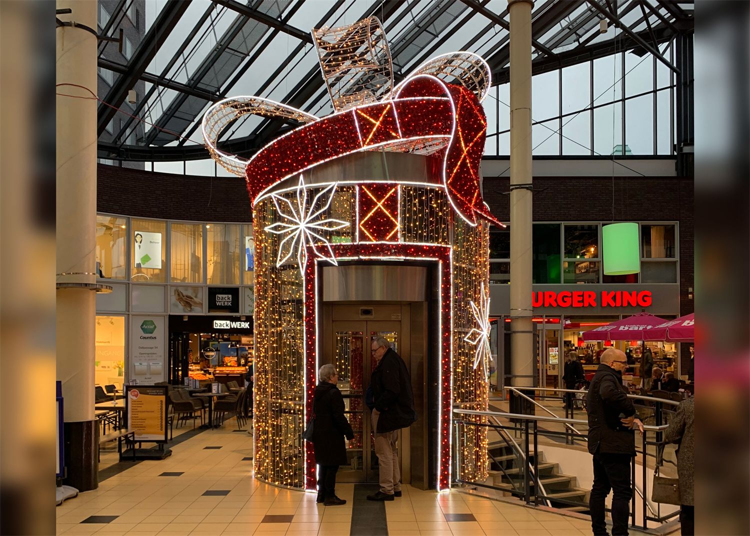 Lift in een winkelcentrum ingepakt als groot rood cadeau met verlichte strik