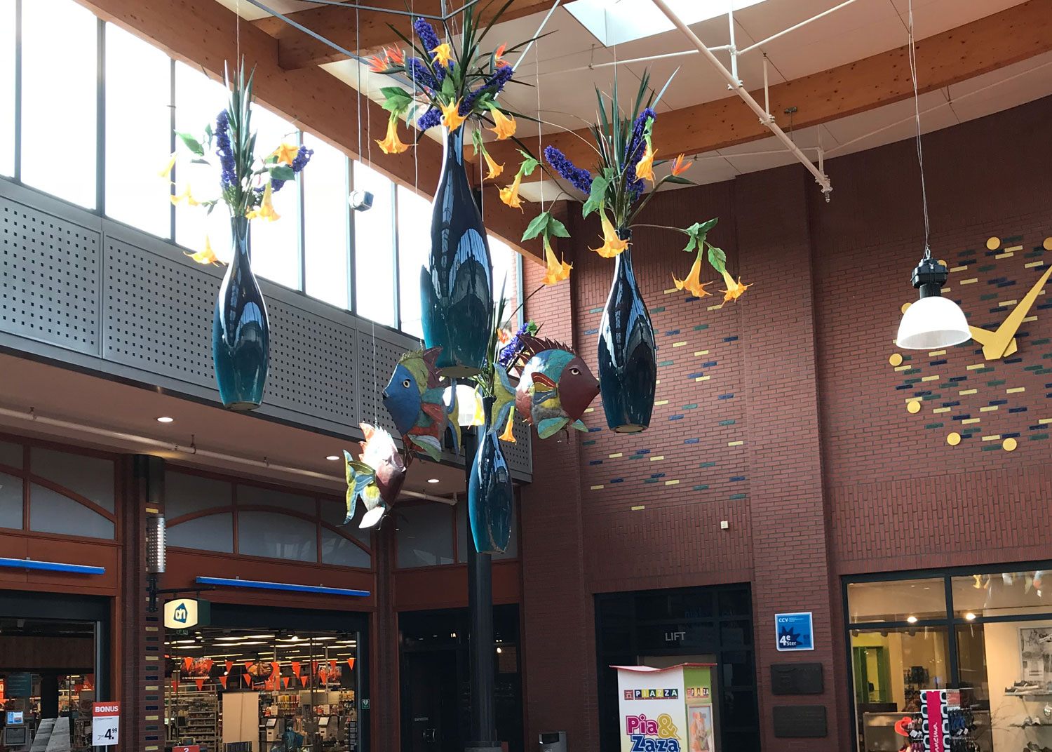 Hangende glazen vazen met felgekleurde bloemen